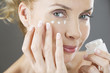 A middle-aged woman applying eye cream