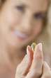 A middle-aged woman holding a vitamin supplement capsule