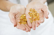 A woman holding a handful of vitamin supplement capsules