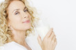 A middle-aged woman holding a glass of milk