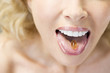 A middle-aged woman with a vitamin capsule on her tongue