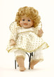 A baby doll in her own wrought iron chair.