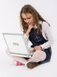 Adorable school girl sitting on floor with laptop computer