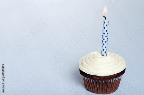 chocolate cupcake with vanilla frosting and a candle