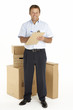 Portrait Of Courier Standing with Parcels, Holding A Clipboard