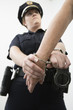 Close up of a person being hand cuffed by a police woman.