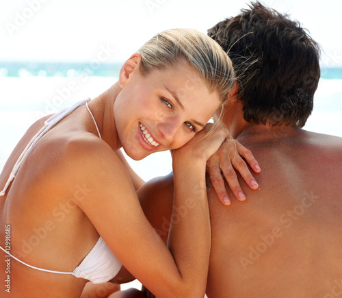 Photo: Lovely young female sitting with her boyfriend at the sea Lovely young female sitting with her boyfriend at the sea