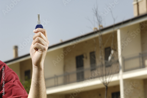 Photo: young man and new home, looking building with door key in hand; young man and new home, looking building with door key in hand;