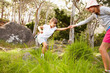 Young girl extending her hand to help her sister to jump