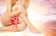 Female legs with pink lily over heaven background Female legs with pink lily over heaven background