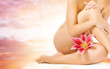 Female legs with pink lily over heaven background Female legs with pink lily over heaven background