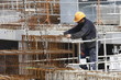 Ouvrier positionne du treilli à l'aide d'une grue