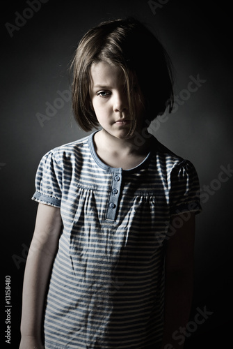 Photo: Low Key Shot of a Sad Little Girl against Grey Background Low Key Shot of a Sad Little Girl against Grey Background