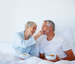 Senior man being feed fruits by wife while still in bed