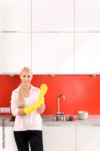 Photo: Woman wearing rubber gloves standing in kitchen Woman wearing rubber gloves standing in kitchen
