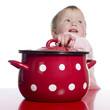 Toddler pretending to cook with a big red pot.