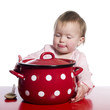 Toddler pretending to cook with a big red pot.