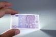 Human fingers holding little euro notes currency