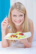 woman eating salad in bed