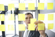 mann in anzug arbeitet hinter scheibe mit post it