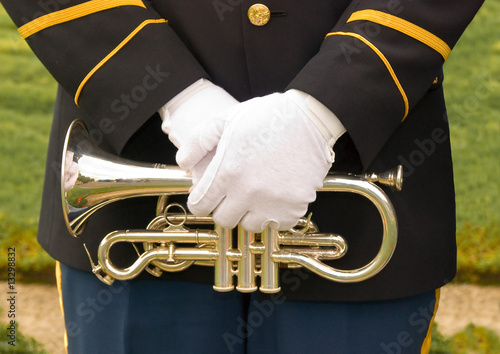 Photo: Uniformed military bugler's gloved hands over trumpet. Uniformed military bugler's gloved hands over trumpet.