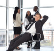 manager relaxing in office with team in background