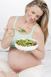 Pregnant woman in bed eating salad