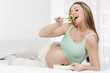 Pregnant woman in bed eating salad