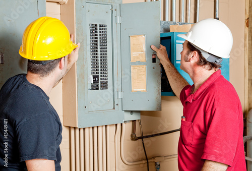 Photo: Repairmen Examine Electrical Panel Repairmen Examine Electrical Panel