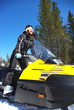 Smiling young woman riding a snowmobile