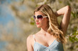 Blond young woman standing under blooming tree