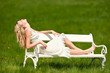 Blond young woman sitting on white bench