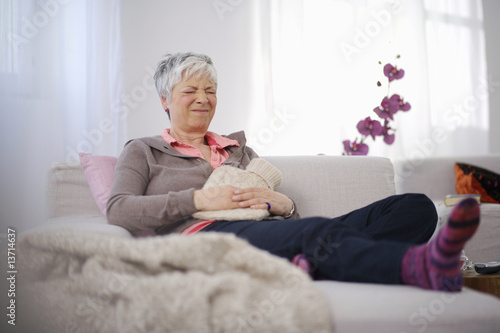 Photo: Senior woman sitting on couch in pain Senior woman sitting on couch in pain