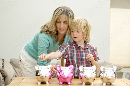 Photo: Mother and son putting coin in piggy bank, Den Haag, Netherlands Mother and son putting coin in piggy bank, Den Haag, Netherlands