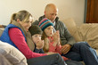 Family in winter clothes keeping warm together on sofa