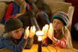 Family in winter clothes warming hands with a light bulb