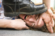 Photo: Young man lying on ground being stepped on by someone wearing black boot Young man lying on ground being stepped on by someone wearing black boot