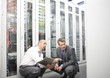 Two mature men crouching down in a computer server room