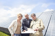 Photo: Three mature adults reading plans in front of solar panels in Munich, Bavaria, Germany Three mature adults reading plans in front of solar panels in Munich, Bavaria, Germany