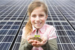 Young girl holding seedling and soil in front of solar panels in Munich, Bavaria, Germany