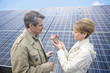 Mature couple standing in front of solar panels holding miniature house in Munich, Bavaria, Germany