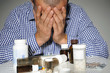 Man surrounded by medicine bottles, studio shot
