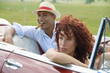 Young multi-ethnic couple in car, man smoking in background, Havana, Cuba