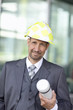 Portrait of mature man in suit wearing hardhat and holding tube container