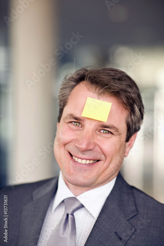 Photo: Portrait of mature man with note paper stuck on forehead Portrait of mature man with note paper stuck on forehead