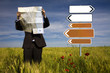 businessman lost in field using a map - sign direction