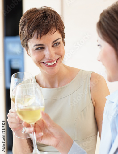 Two female celebrating with a glass of white wine