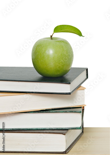 Green apple on pile of books