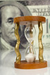 hourglass on big dollar background hourglass on big dollar background