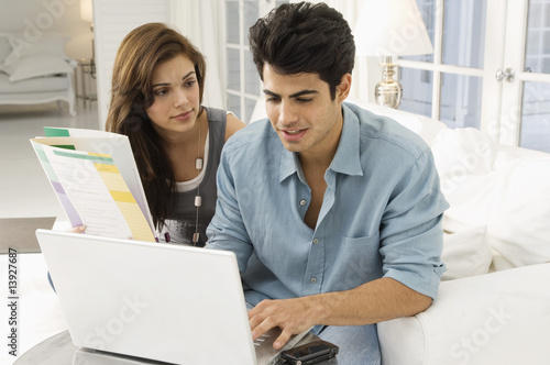 Photo: Man using a laptop with a woman sitting beside him Man using a laptop with a woman sitting beside him